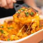 Low carb dump and bake pasta casserole being served from a baking dish with melted cheese and green onions
